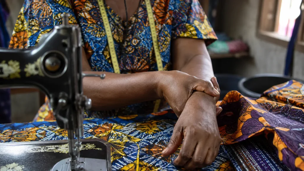Mains d'une couturière camerounaise au repos près de sa machine à coudre
